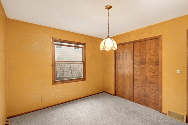 unfurnished bedroom with a baseboard heating unit, visible vents, baseboards, a closet, and carpet