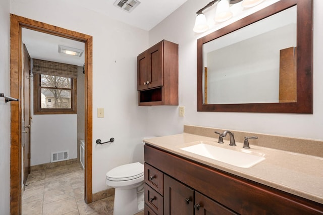 full bathroom featuring toilet, vanity, visible vents, and baseboards