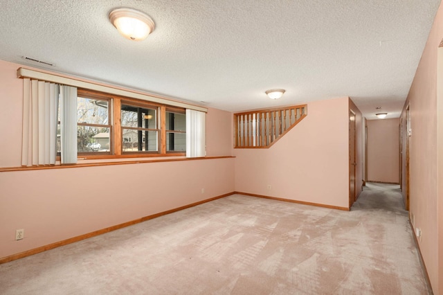 spare room featuring carpet, visible vents, a textured ceiling, and baseboards