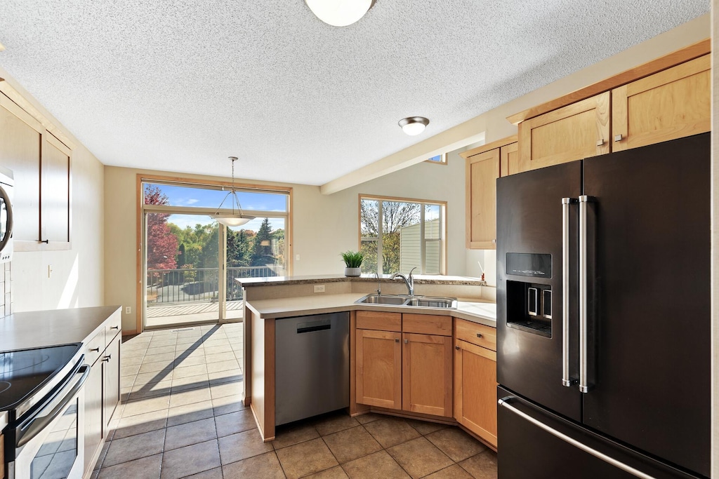 kitchen featuring light tile patterned flooring, sink, light brown cabinets, pendant lighting, and stainless steel appliances