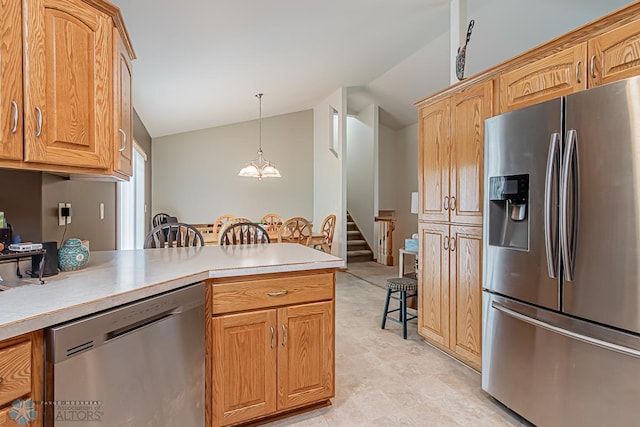 kitchen with appliances with stainless steel finishes, pendant lighting, light countertops, and vaulted ceiling