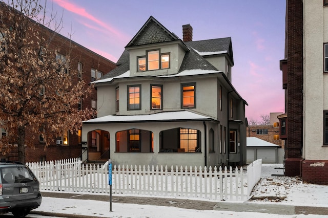 view of front facade with a porch, stucco siding, a fenced front yard, and a chimney