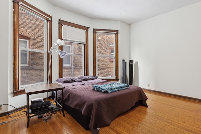 bedroom with wood-type flooring, multiple windows, and a textured ceiling