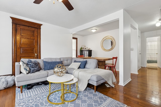 living room featuring dark wood-type flooring and ceiling fan