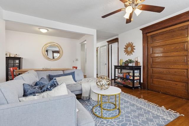 living room featuring dark wood-type flooring and ceiling fan