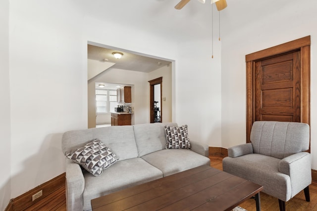 living area with baseboards, a ceiling fan, and wood finished floors