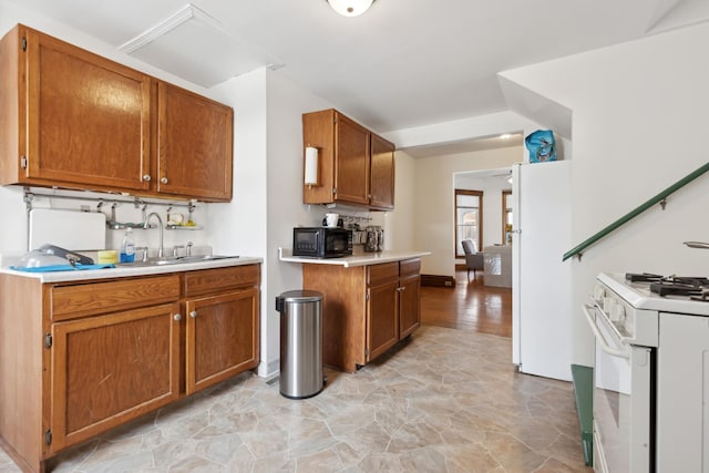 kitchen with a sink, light countertops, white appliances, and brown cabinets