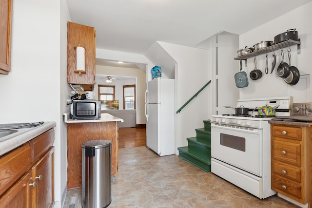 kitchen featuring light countertops, brown cabinetry, white appliances, and ceiling fan