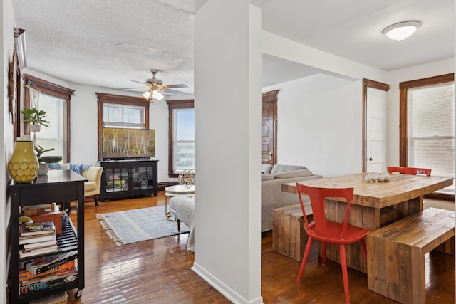 dining room with dark wood-type flooring, ceiling fan, baseboards, and a textured ceiling