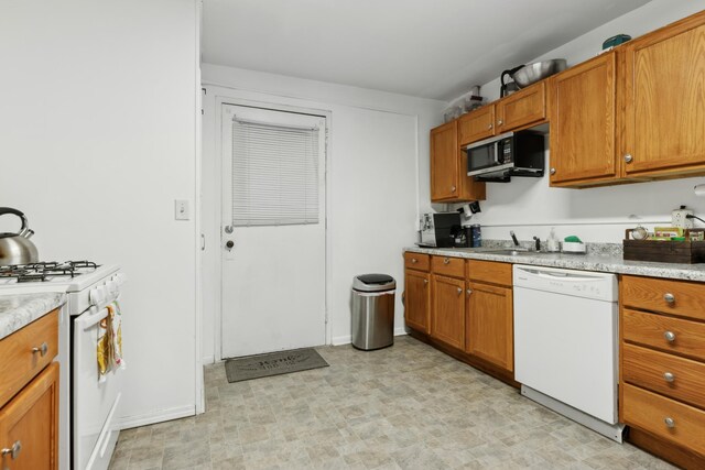 kitchen featuring light countertops, brown cabinets, a sink, and white appliances