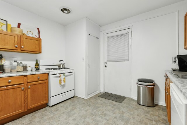 kitchen with white appliances, visible vents, brown cabinets, and light floors