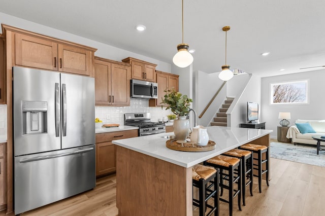 932 Orchard Ln, Roseville, MN 55113 - kitchen with appliances with stainless steel finishes, light wood-style flooring, light countertops, backsplash, and a center island with sink