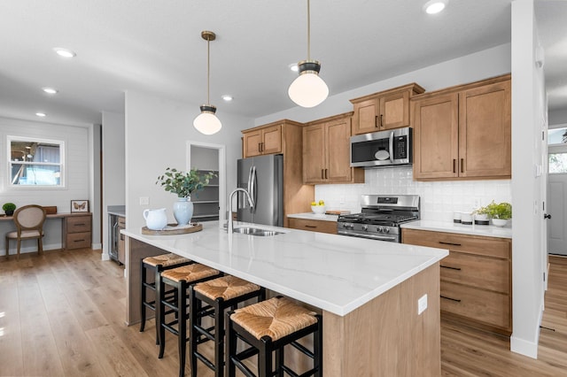 932 Orchard Ln, Roseville, MN 55113 - kitchen with stainless steel appliances, light wood-style flooring, decorative backsplash, brown cabinets, and a center island with sink