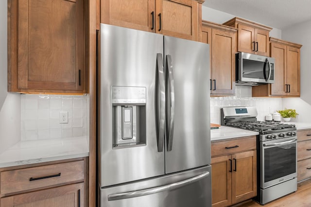 932 Orchard Ln, Roseville, MN 55113 - kitchen featuring appliances with stainless steel finishes, decorative backsplash, light stone counters, and light wood-type flooring
