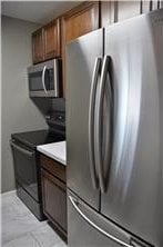 kitchen featuring appliances with stainless steel finishes, brown cabinetry, and light countertops