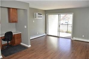 home office with dark wood-style flooring, baseboards, baseboard heating, and a wall mounted air conditioner