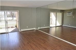 unfurnished room featuring a wall unit AC and wood finished floors