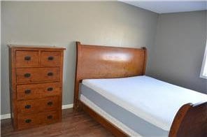 bedroom with dark wood finished floors and baseboards