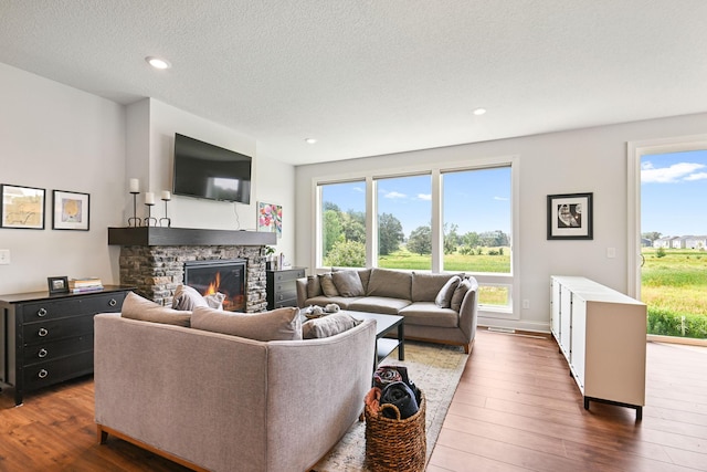 living room with dark hardwood / wood-style flooring, a textured ceiling, and a fireplace