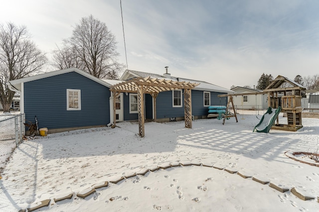 snow covered back of property featuring a playground