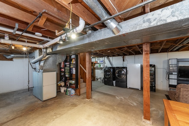 basement with separate washer and dryer, heating unit, and white refrigerator