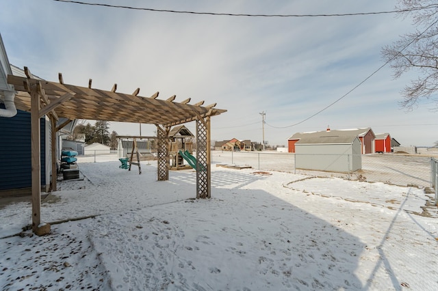 yard layered in snow featuring a playground and a storage unit