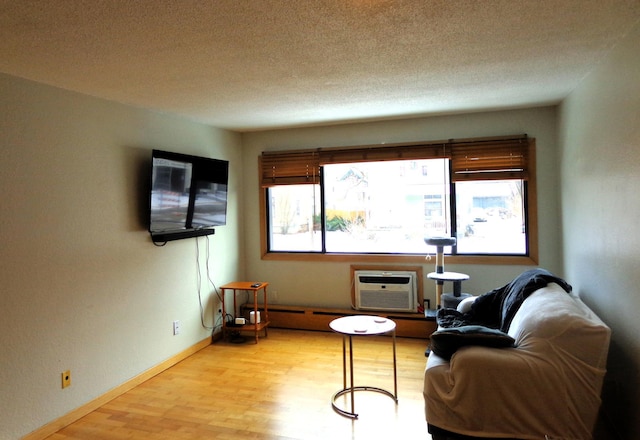 sitting room featuring a textured ceiling, a wall unit AC, and light hardwood / wood-style flooring