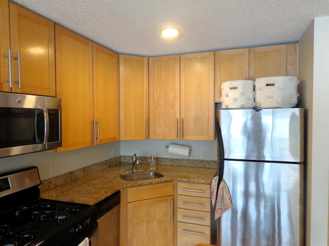 kitchen featuring sink, stainless steel appliances, light stone counters, a textured ceiling, and light brown cabinetry