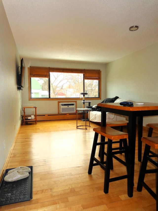 dining room featuring plenty of natural light, a wall mounted air conditioner, and light wood-type flooring