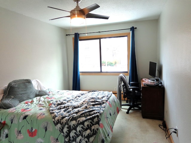 bedroom with ceiling fan, light carpet, and a textured ceiling