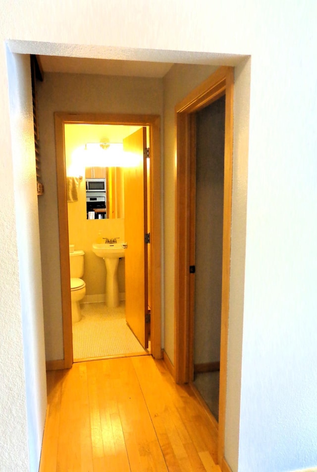 corridor featuring sink and light hardwood / wood-style flooring