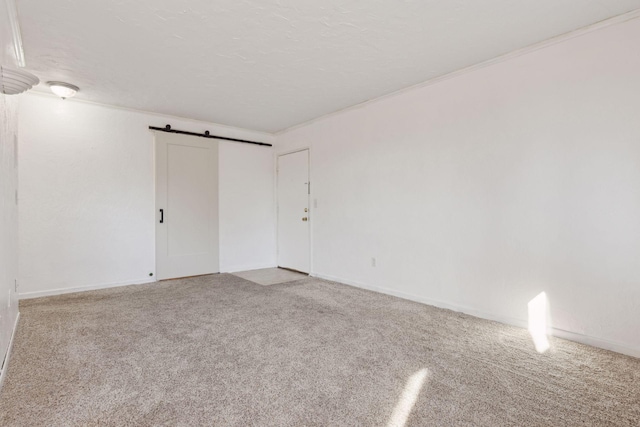 spare room featuring ornamental molding, a barn door, a textured ceiling, and carpet flooring