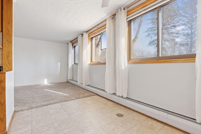 carpeted spare room with a baseboard radiator and a textured ceiling