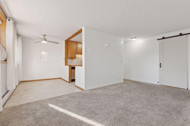 unfurnished living room featuring ceiling fan, a barn door, light carpet, and a textured ceiling