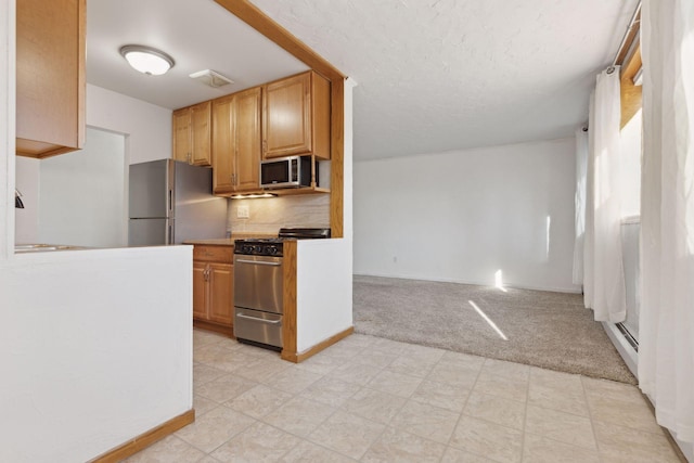 kitchen with sink, light carpet, appliances with stainless steel finishes, a baseboard heating unit, and backsplash