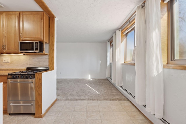 kitchen featuring light carpet, backsplash, stainless steel appliances, and a textured ceiling