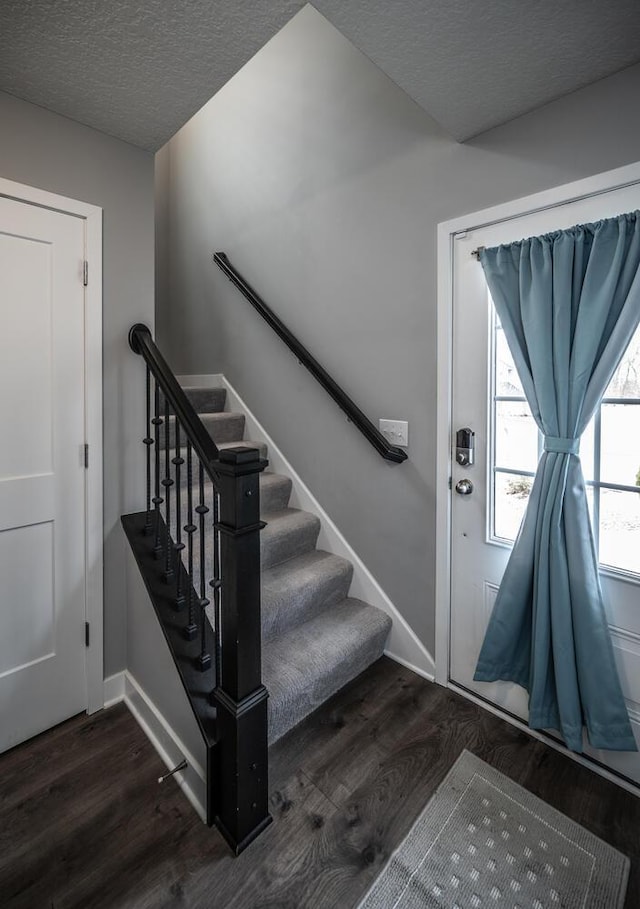 foyer featuring stairway, baseboards, a textured ceiling, and dark wood-style flooring