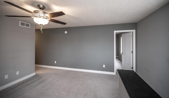 empty room with visible vents, carpet flooring, baseboards, and a ceiling fan