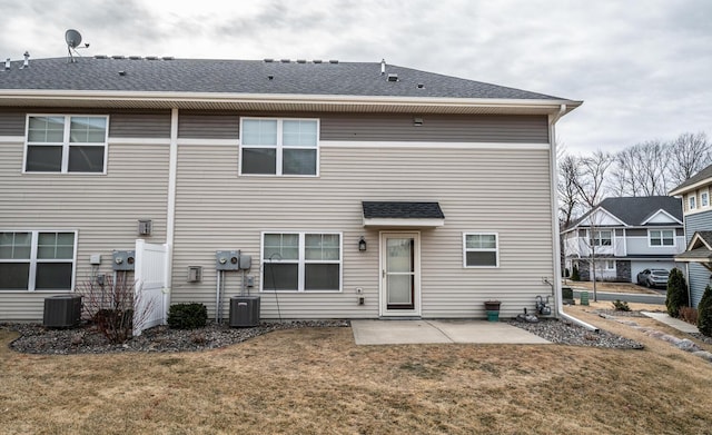 rear view of house featuring a yard, a patio area, central AC, and a shingled roof