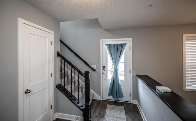 doorway to outside featuring stairway, baseboards, a textured ceiling, and dark wood-style flooring