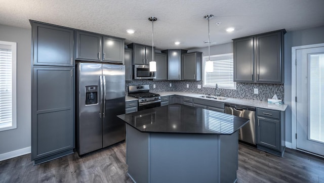 kitchen with dark wood finished floors, decorative backsplash, appliances with stainless steel finishes, and a sink