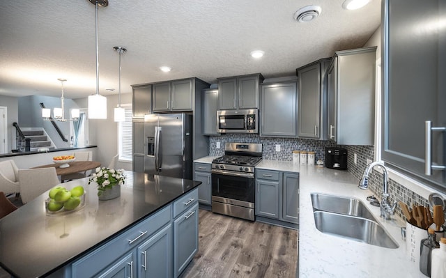 kitchen featuring a sink, decorative light fixtures, backsplash, dark wood finished floors, and stainless steel appliances