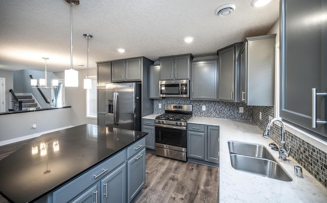 kitchen with a sink, decorative backsplash, appliances with stainless steel finishes, and dark wood finished floors