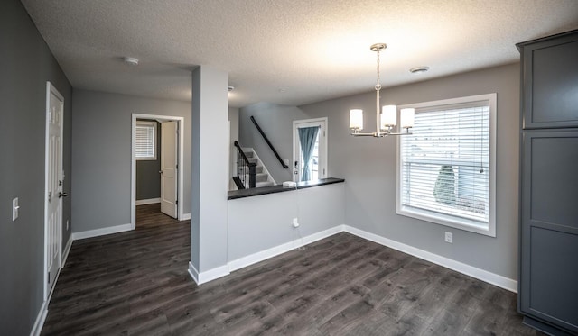 unfurnished dining area featuring stairs, dark wood finished floors, baseboards, and a textured ceiling