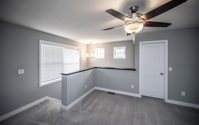 carpeted spare room featuring visible vents, a textured ceiling, and baseboards