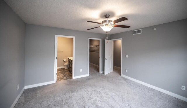 unfurnished bedroom with visible vents, a textured ceiling, a closet, baseboards, and a spacious closet