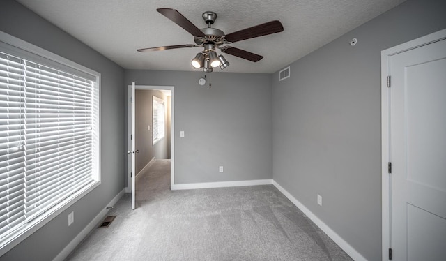 unfurnished bedroom featuring visible vents, carpet flooring, a textured ceiling, and baseboards