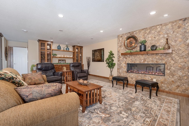 living room with a textured ceiling, recessed lighting, a fireplace, wood finished floors, and baseboards