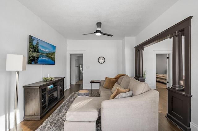 living room with decorative columns, dark wood-type flooring, a textured ceiling, and ceiling fan