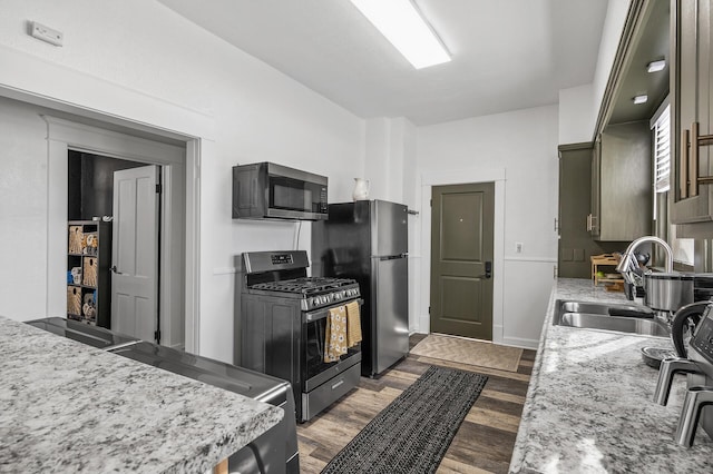 kitchen featuring light stone counters, appliances with stainless steel finishes, light hardwood / wood-style floors, and sink